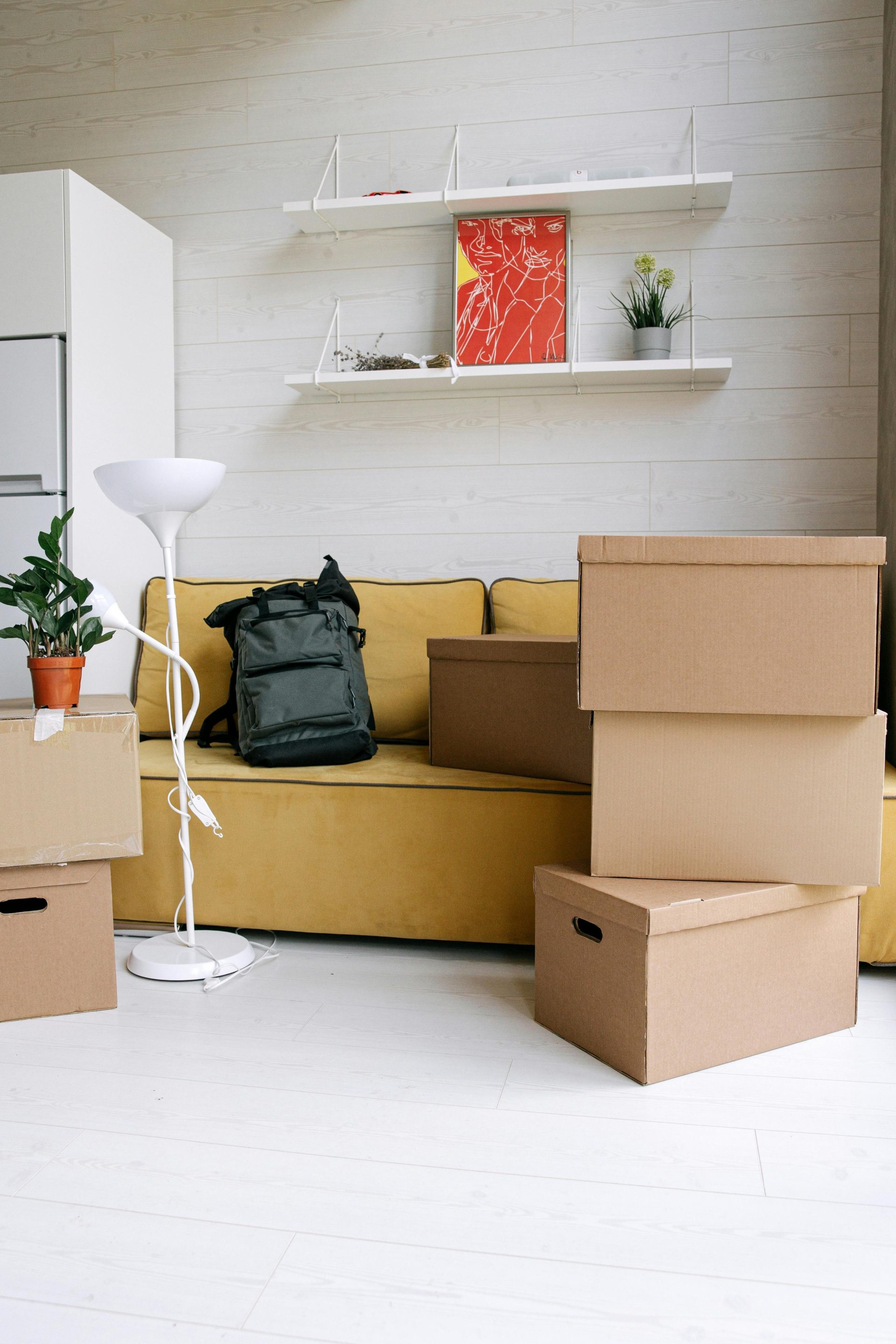 Modernes Wohnzimmer mit gelbem Sofa und Umzugskartons, perfekt für Einzugsthemen.